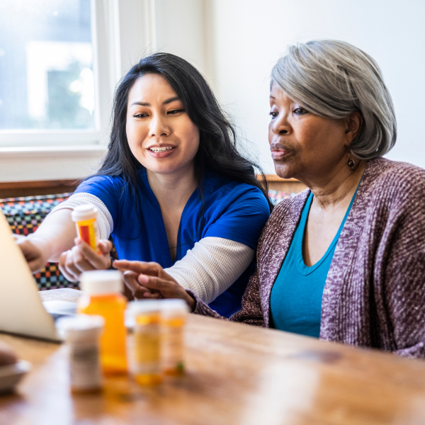 nurse helping elderly woman take prescription medication