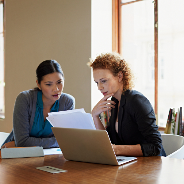 Two women reviewing paperwork at a conference room table