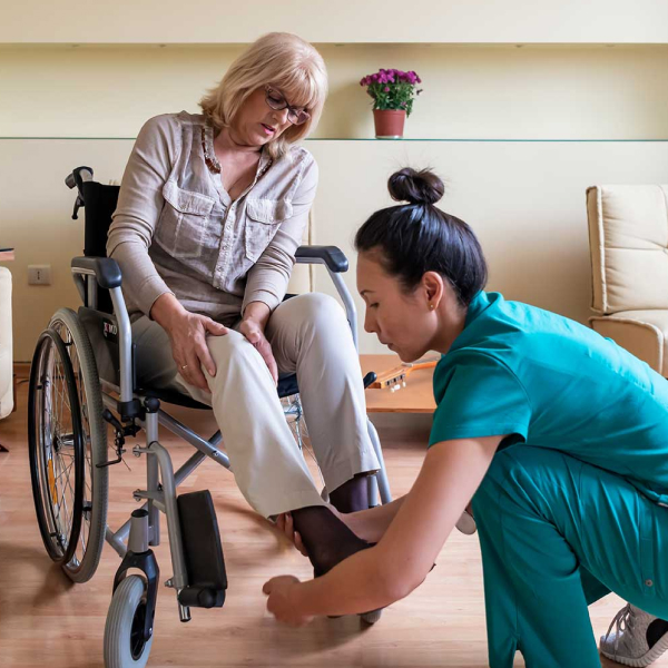 Nurse helping woman in wheelchair reposition her legs